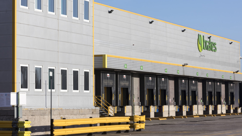 Large industrial warehouse with multiple loading docks and Brakes signage, modern UK logistics facility